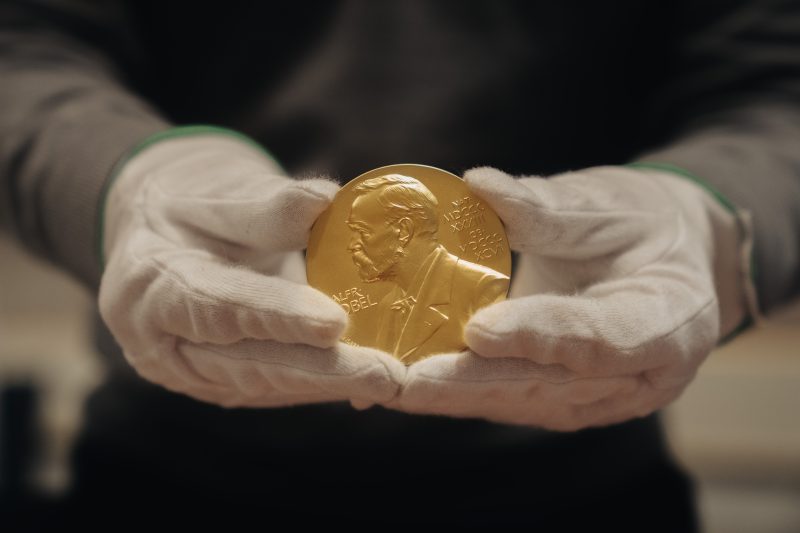 Nobel Prize Medal held by hands in gloves