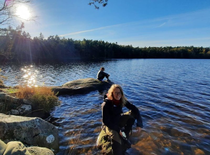 Foto of the blogger out in nature with a lake view on a sunny day.