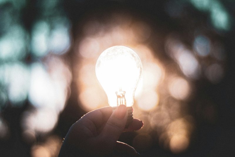 Hand holding a bright lightbulb.